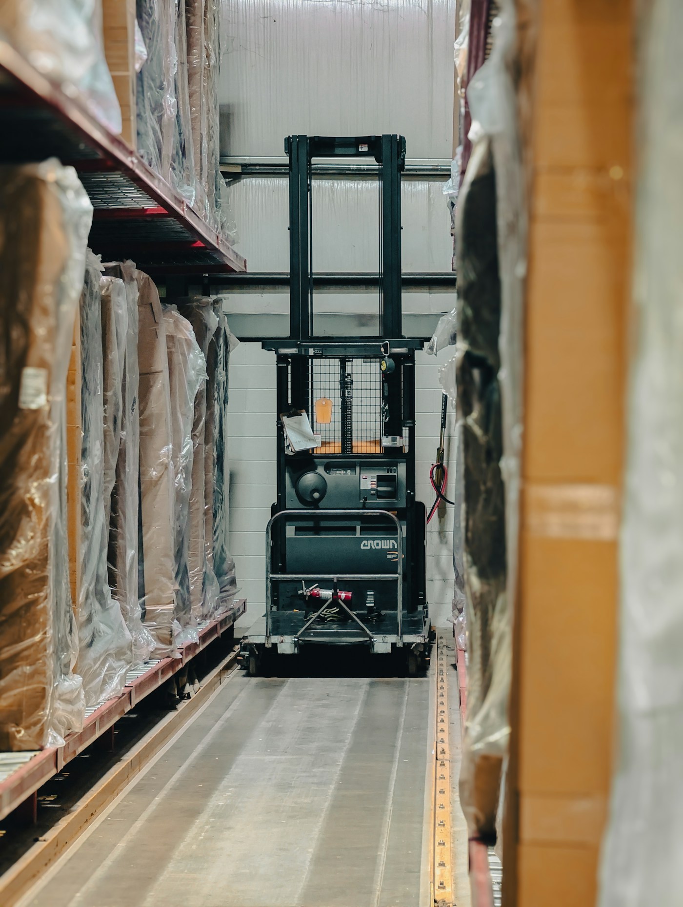 Forklift operating between warehouse storage racks